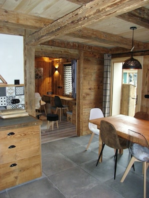 A rustic wooden interior with a dining area, a wooden cabinet with drawers, and a tiled floor. - Chalet with view, in a quiet area, close to all services in summer and winter. (Saint-Gervais-les-Bains)