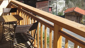 A wooden deck with a table and chairs, overlooking a mountainous village with houses and a clear sky. - Chalet with view, in a quiet area, close to all services in summer and winter. (Saint-Gervais-les-Bains)