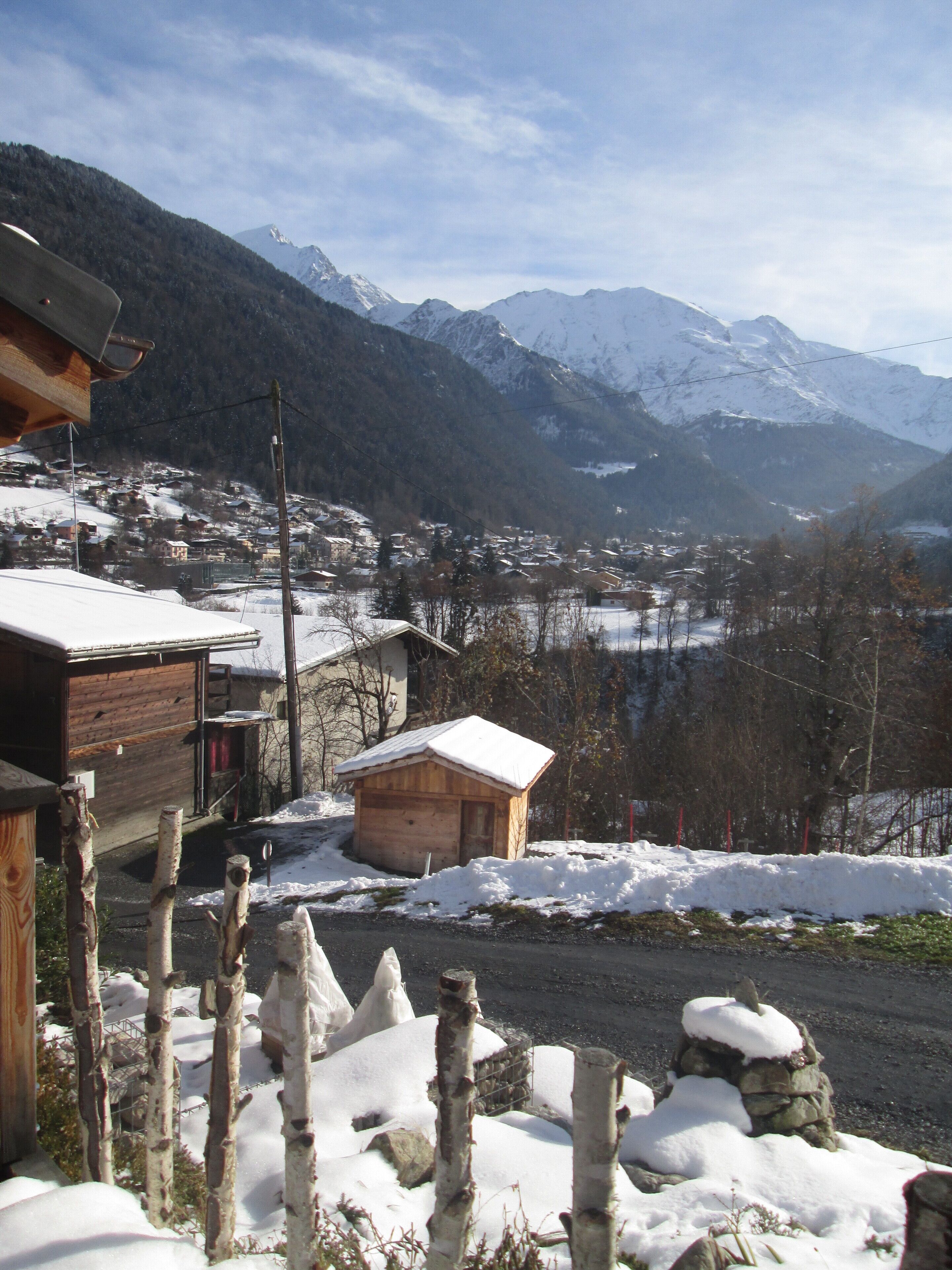 A snow-covered mountain village with wooden buildings and a clear view of the surrounding mountains.