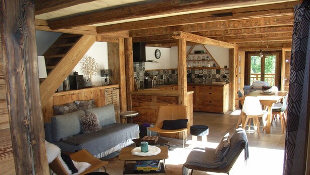 A rustic interior with a wooden dining area, a kitchen with a tiled backsplash, and a living room with a sofa and chairs. - Chalet with view, in a quiet area, close to all services in summer and winter. (Saint-Gervais-les-Bains)