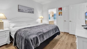 A bedroom with a bed, bedside tables, a nightstand, a wardrobe, and a door leading to another room. - Myrtlewood Villa Lake View 2BR/2fullBA in Central Myrtle Beach (Myrtle Beach)