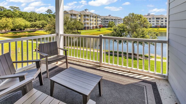 A balcony with a view of a lake, a golf course, and apartment buildings. - Myrtlewood Villa Lake View 2BR/2fullBA in Central Myrtle Beach (Myrtle Beach)
