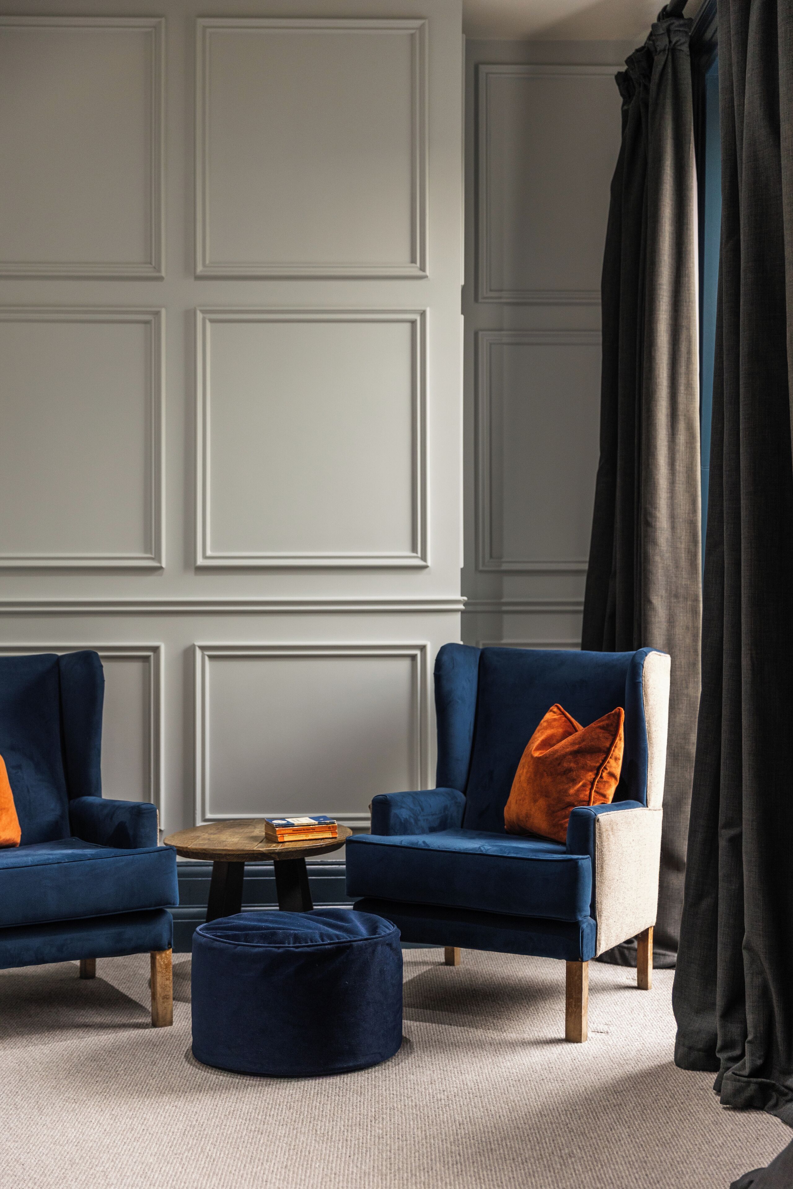 A living room with two blue armchairs, a round coffee table, and a matching ottoman.