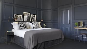 A bedroom with a large bed, dark walls, and a desk with a mirror.