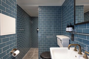 A bathroom with blue-tiled walls, a white sink with a brass faucet, and a toilet.