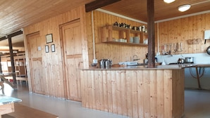 A wooden interior with a kitchen area, including a counter, sink, and various kitchen utensils. - Hólaskjól Highlandcenter (Kirkjubaejarklaustur)