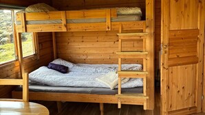 A wooden cabin with bunk beds, a small table, and a door. - Hólaskjól Highlandcenter (Kirkjubaejarklaustur)