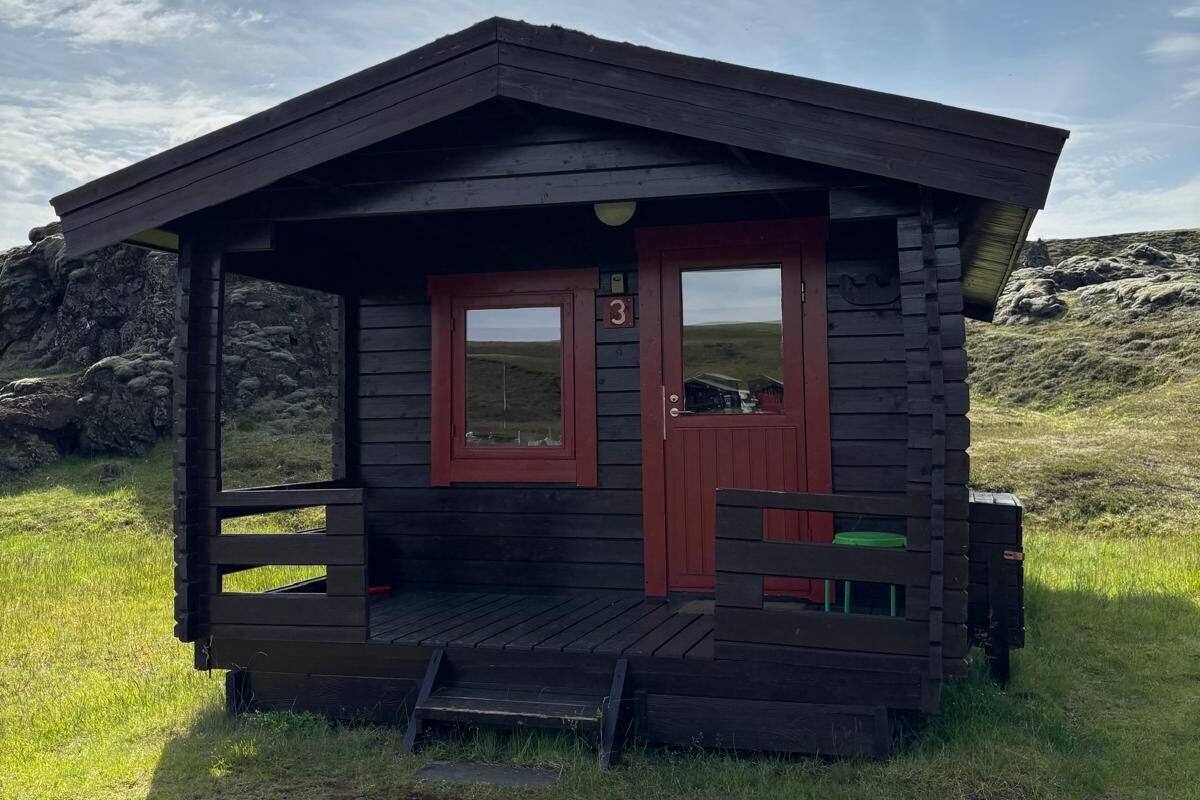 A small wooden cabin with a porch, a door, and a window.