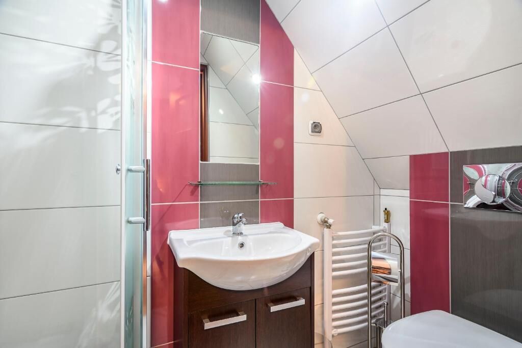 A modern bathroom with a white sink, a glass shelf, and a towel rack.
