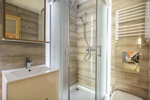 Une salle de bain moderne avec une douche à parois de verre, un lavabo et un miroir.