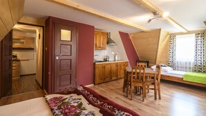 Una habitación acogedora y funcional, con cama, mesa de comedor y kitchenette.
