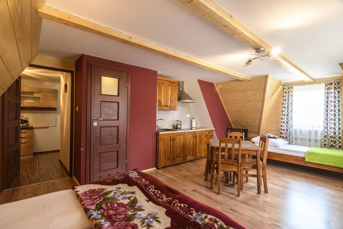 A cozy, compact room with a bed, a dining table, and a kitchenette.
