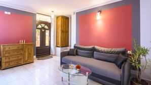 Una sala de estar moderna con un sofá, una mesa de centro de vidrio, un aparador de madera y una planta en maceta.
