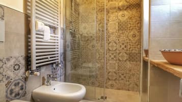 A bathroom with a shower enclosure, a bidet, and a toilet.