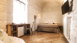 Una habitación acogedora con un escritorio de madera, una cama y un televisor montado en la pared.