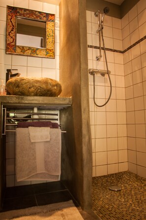 A bathroom with a tiled shower, a mirror with a mosaic frame, and a towel rack with a folded towel. - Les deux chemins (Mons)