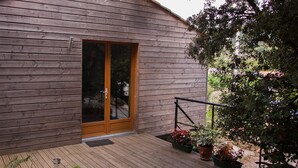 A wooden cabin with a sliding glass door, a wooden deck, and potted plants. - Les deux chemins (Mons)