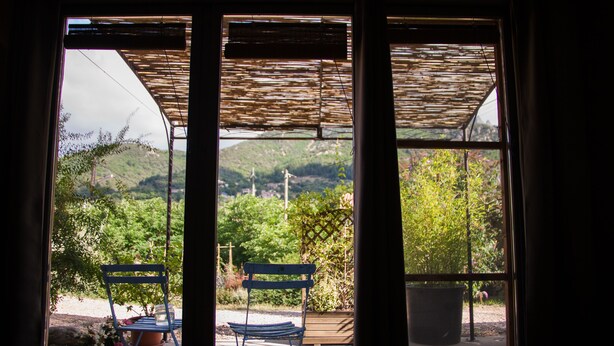 A view through a window with a wooden bench and potted plants. - Les deux chemins (Mons)