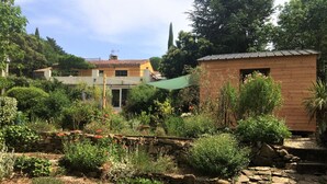 A garden with a stone wall, various plants, and a wooden structure. - Les deux chemins (Mons)