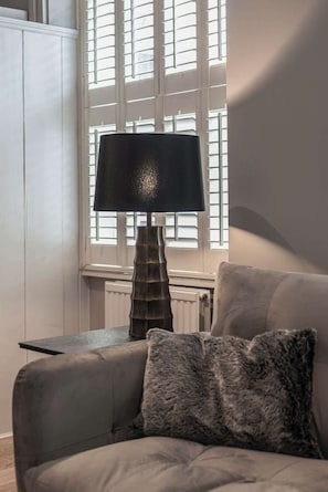 A room with a sofa, a lamp, and a window with blinds.