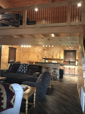 A cozy cabin interior with a living room, kitchen, and a balcony. - Beautiful 3 bed / 3 bath Luxury Cabin, Hot Tub, Games, Easy Check in! Book Now! (Sevierville)