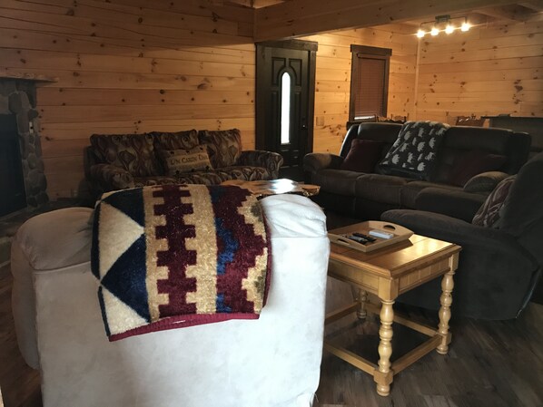 A cozy living room with a wooden interior, a sofa, a coffee table, and a blanket on a chair. - Beautiful 3 bed / 3 bath Luxury Cabin, Hot Tub, Games, Easy Check in! Book Now! (Sevierville)