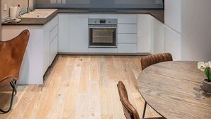 Una cocina moderna con tragaluz, suelo de madera y comedor con mesa y sillas.
