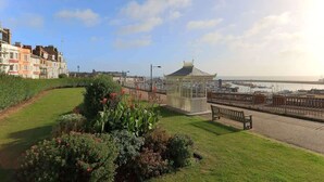 Un paseo marítimo con un mirador, bancos y vista al mar.