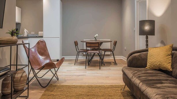 Una sala moderna con sofá, una mesa de comedor con sillas, una zona de cocina y un tragaluz.