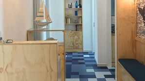 A hallway with a checkered floor, a wooden bench, a chandelier, and a bookshelf with decorative items. - Il Grande Blu (Terracina)