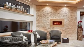Una sala de estar acogedora con sofás de estampado pata de gallo, una mesa de centro de vidrio y una pared de piedra con chimenea.