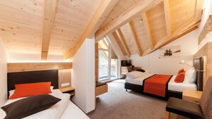 Un dormitorio acogedor en el ático con dos camas, un televisor y un escritorio pequeño.