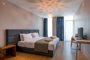 A modern hotel room with a large bed, a desk, and a television. - The Berg Hotel (Borjomi)