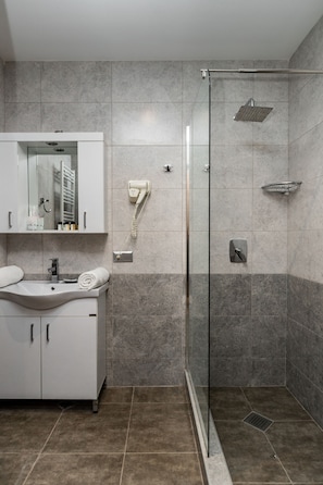 A modern bathroom with a glass-enclosed shower, a white vanity with a sink, and a mirror above it. - The Berg Hotel (Borjomi)