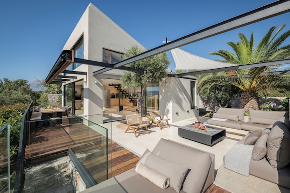 A modern outdoor living area with a wooden deck, outdoor seating, and a large white canopy.
