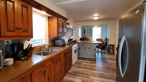 A kitchen with wooden cabinets, a microwave, a toaster, a sink, and a refrigerator. - Antebellum home (Chauvin)