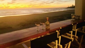 A bar with a view of the beach and ocean at sunset.