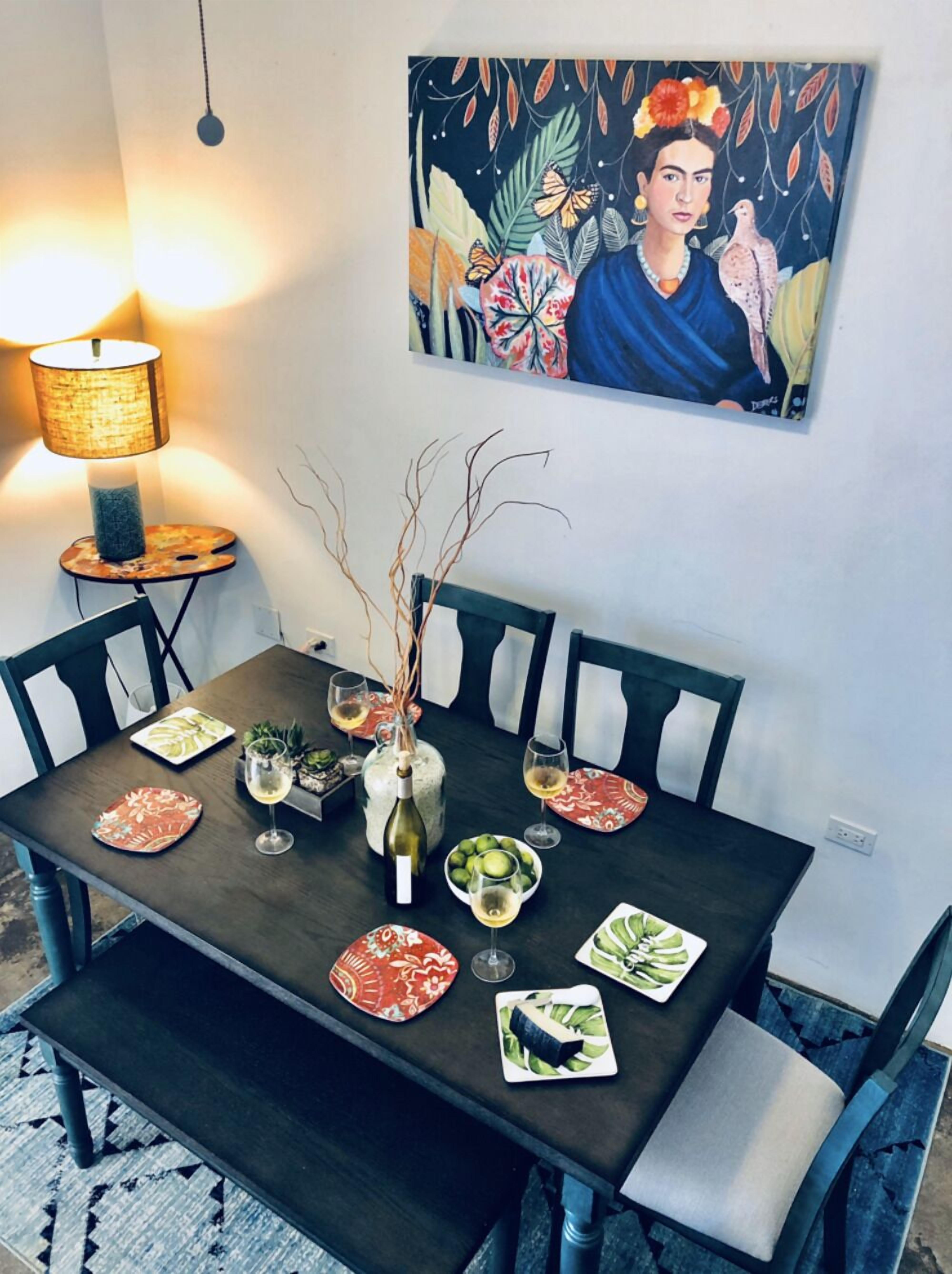 Une table à manger dressée avec des assiettes, des verres et une bouteille de vin, entourée de chaises.