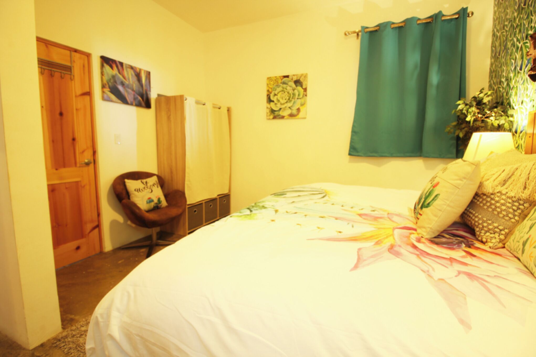 A bedroom with a bed, a chair, a door, and a curtain.
