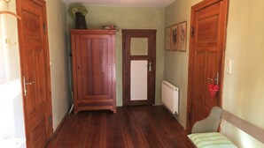 Un couloir doté d’un plancher en bois, d’un radiateur, d’un banc avec des coussins à rayures et de portes en bois.