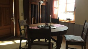 Un coin repas comprenant une table ronde, des chaises, un buffet et une fenêtre avec des rideaux.