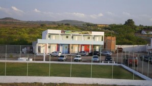 A multi-story building with a parking lot in front. - Pousada Nathymar (Piranhas)