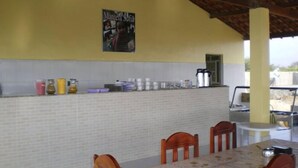 A dining area with a tiled backsplash, a poster on the wall, and a table with chairs. - Pousada Nathymar (Piranhas)