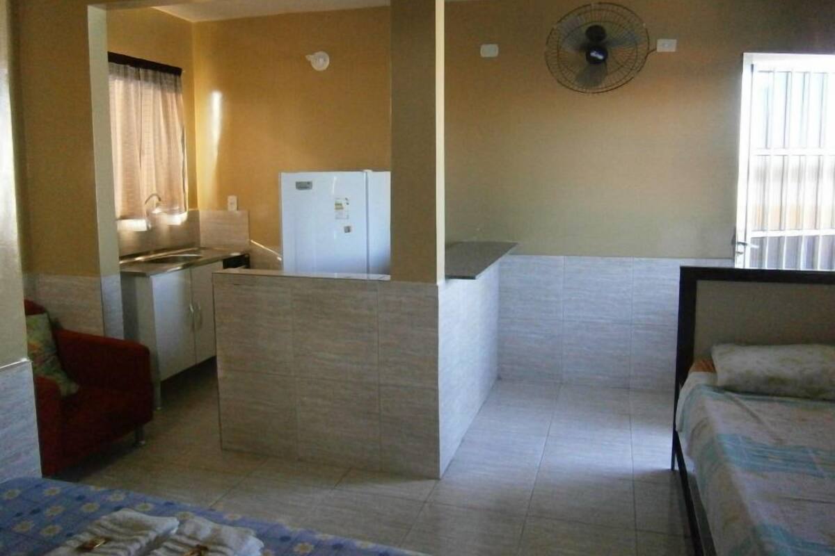 Une chambre d’hôtel compacte comprenant un coin cuisine, un lit simple et un petit espace salon.