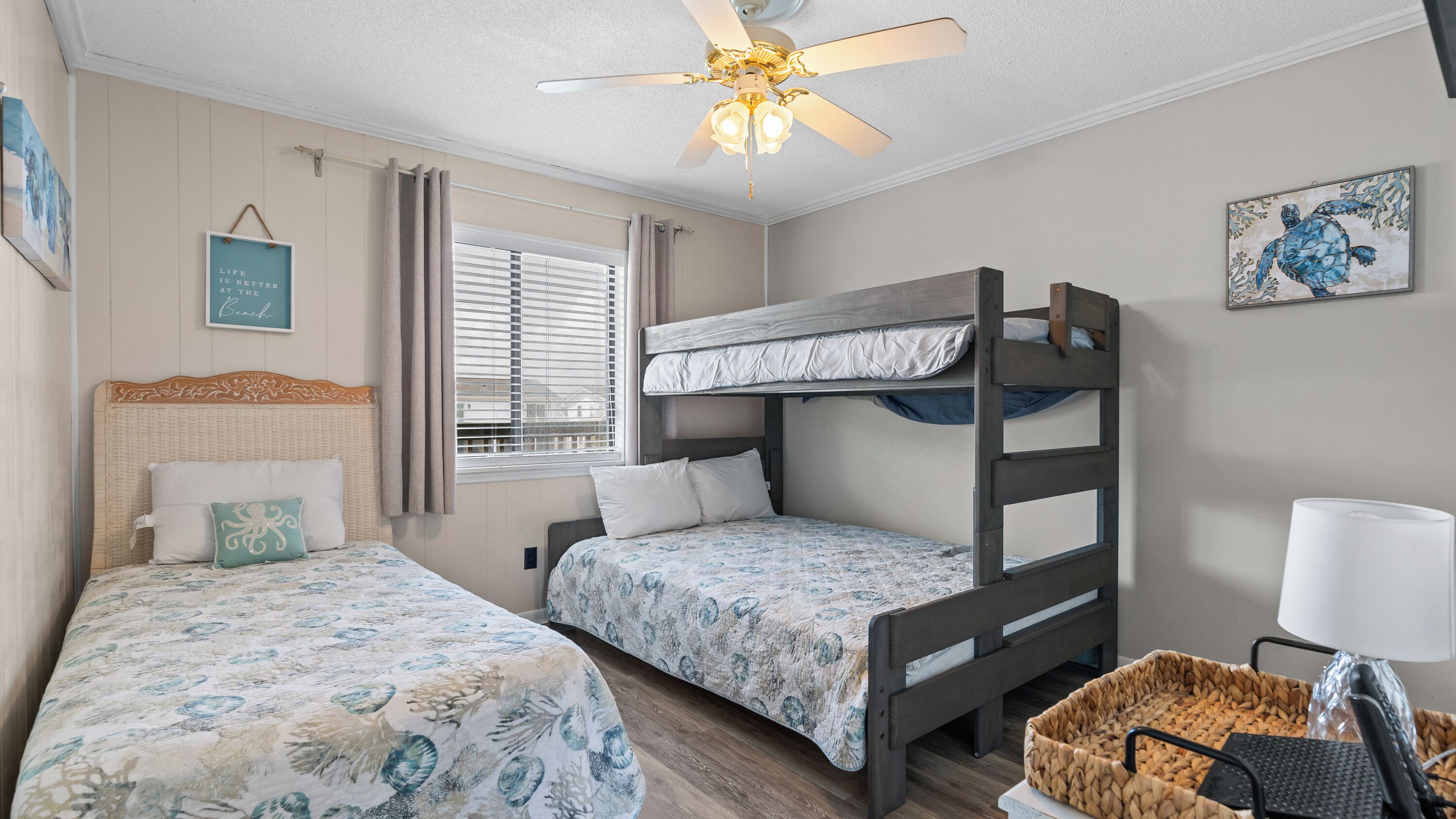 A bedroom with two bunk beds, a ceiling fan, a window with blinds, and a wall-mounted lamp.