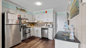 A modern kitchen with stainless steel appliances, white cabinets, and a wooden floor.