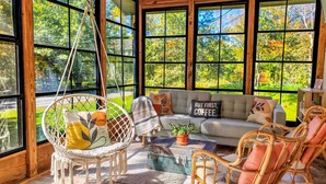 Una habitación acogedora con una hamaca, un sofá y sillones de mimbre.
