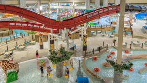 Parque acuático interior con toboganes, piscinas y zonas de juegos.