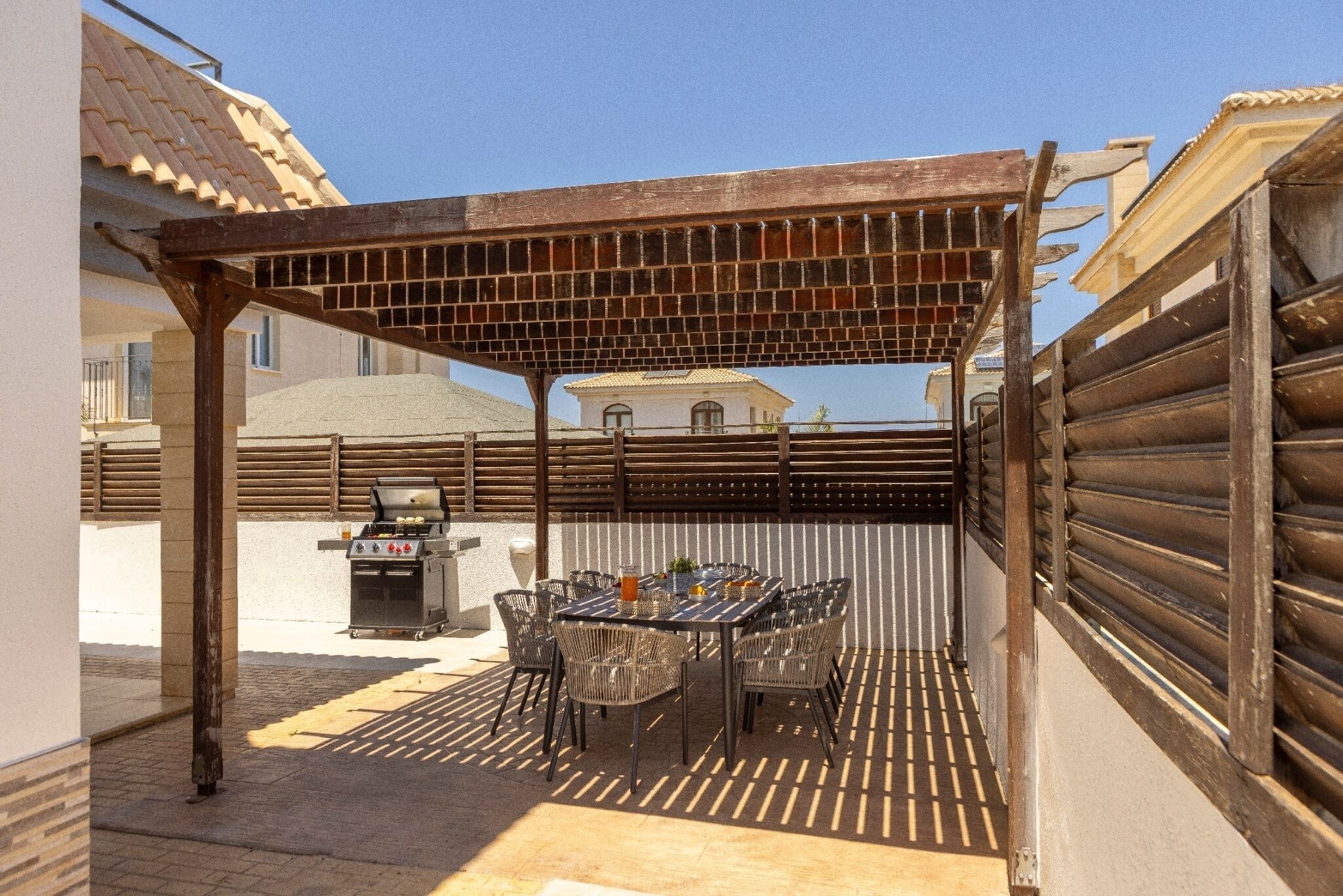 Une terrasse extérieure équipée d’un barbecue, d’une table à manger et de chaises.