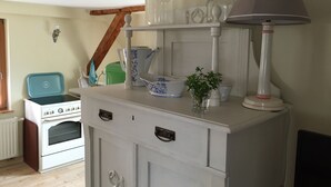 A kitchen with a white stove, a white cabinet with drawers, a small plant on the counter, and a lamp on top. - Apartment Ida up to 6 people (Stuer)